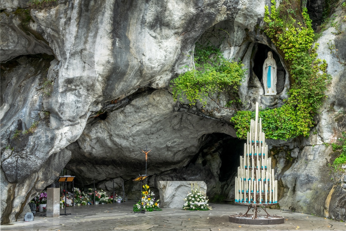 Grotte de Massabielle à Lourdes : Vierge Marie, autel floral et bougies. Inscription « QUE SOY ERA IMMACULADA CONCEPCIOU ».